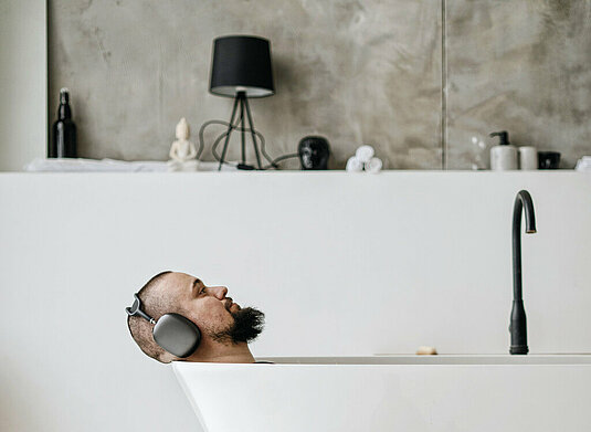 Mann entspannt mit Musik in der Badewanne